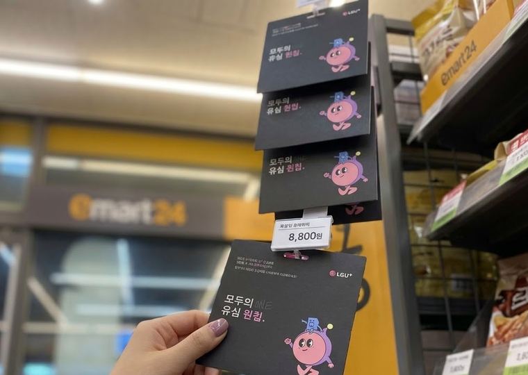 편의점 진열대에 걸린 모두의 원칩과 손에 든 한 장